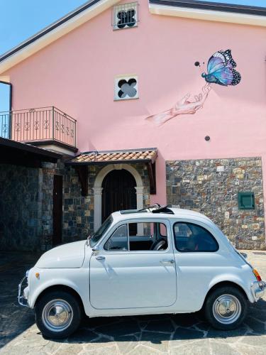 a white car parked in front of a pink building at B&B Girasole in Torraca