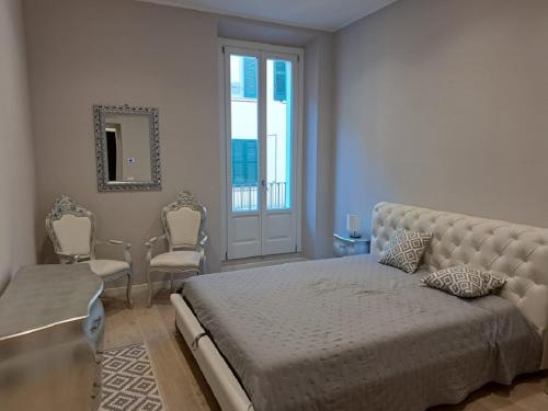 Un dormitorio con una cama y sillas y una ventana. en Eleganti Dimore, en Brescia
