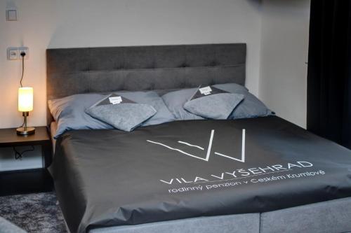 a bed with a gray comforter with the word vm synergy on it at Vila Vyšehrad in Český Krumlov