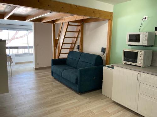un salon avec une chaise bleue et un four micro-ondes dans l'établissement L'Airette, à Marseillan