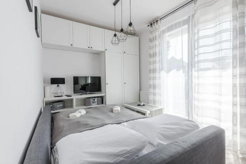 een witte slaapkamer met een bed en een televisie bij Golden Apartments Gdansk&K2A in Gdańsk