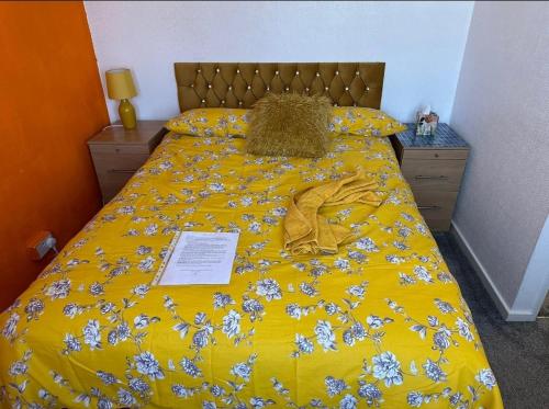 a bed with a yellow bedspread with flowers on it at Quick Stop Night Stay - Gatwick in Crawley