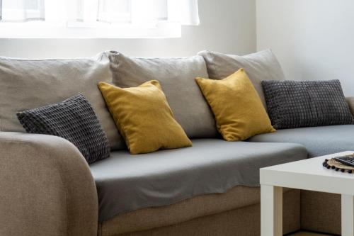 a gray couch with yellow pillows on it at Apartment Pemper - Self check in and check out in Otočac