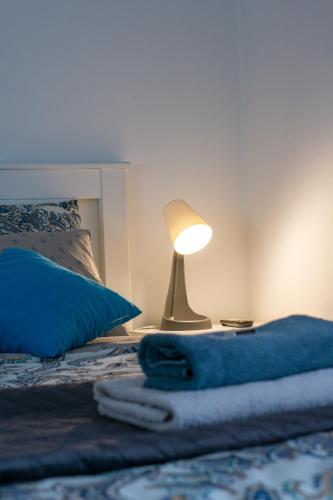 a bed with a blue blanket and a lamp on it at Apartment Pemper - Self check in and check out in Otočac