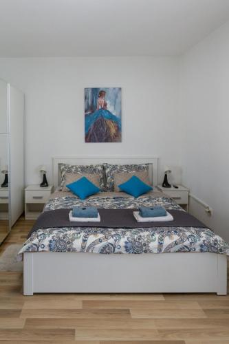 a white bedroom with a large bed with blue pillows at Apartment Pemper - Self check in and check out in Otočac