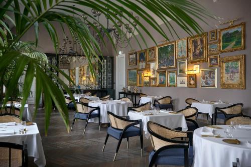 a restaurant with white tables and chairs and paintings on the walls at BOTANIQ Castle of Tura - Small Luxury Hotels of the World in Tura