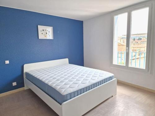 ein Schlafzimmer mit einer blauen Wand und einem weißen Bett in der Unterkunft Spacious 3-bedroom apartment with terrace and AC in the city centre in Avignon