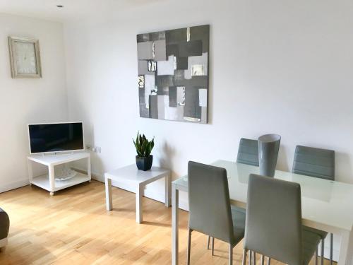 a dining room with a table and chairs and a television at Bedford Central Apartment with Free Secure Parking in Bedford