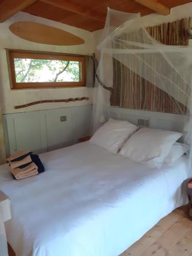 a white bed in a room with a window at La cabane de l'oiseau in Couze-et-Saint-Front