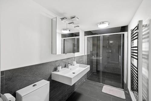 a bathroom with a sink and a toilet and a shower at Chic & Contemporary Apartment with Patio - Parking in Wakefield