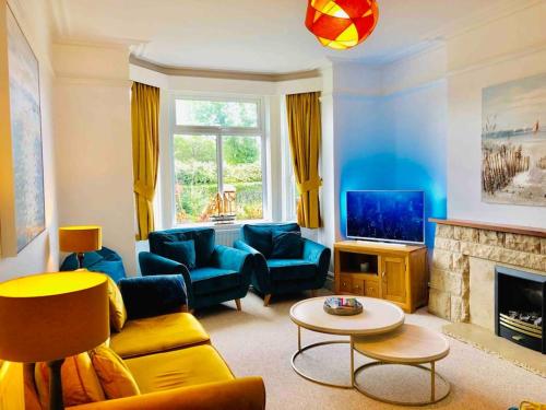 a living room with blue furniture and a fireplace at Sandy Shores, 3 min walk to beach & Swanage centre in Ulwell