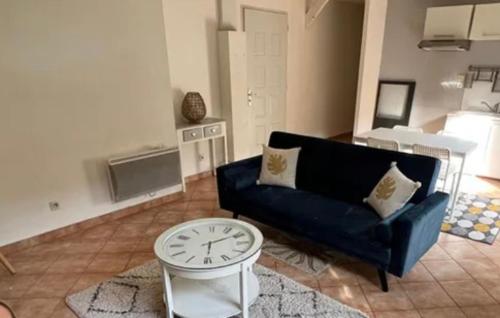 uma sala de estar com um sofá azul e um relógio em Appartement jardin 4 couchages proche aéroport Groupama stadium eurexpo em Saint-Bonnet-de-Mure