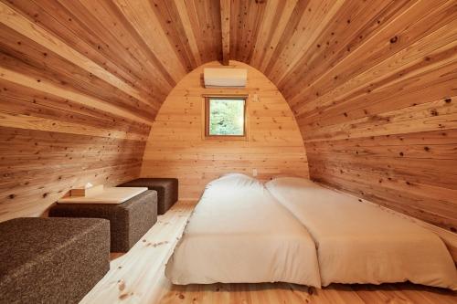 a bedroom in a log cabin with a bed and a table at ミヤマテラス in Nantan city