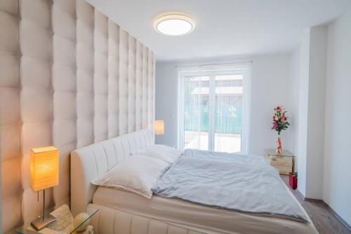 un letto con testiera imbottita bianca in una camera da letto di Luxus Partivilla Apartman a Szántód