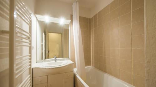 La salle de bains est pourvue d'un lavabo, d'une baignoire et d'un miroir. dans l'établissement Vacancéole - Les Etoiles d'Orion, à Orcières