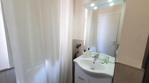 Baño blanco con lavabo y espejo en RomagnaBNB Cignani en Forlì