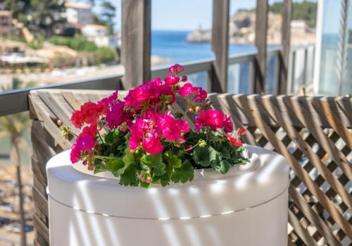 a white bucket filled with pink flowers on a balcony at Los Geranios in Port de Soller