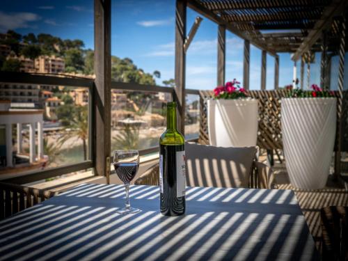 a bottle of wine sitting on a table with a glass at Los Geranios in Port de Soller