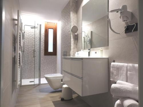 a white bathroom with a toilet and a sink at Apartaments Turistics El Buner in Ordino