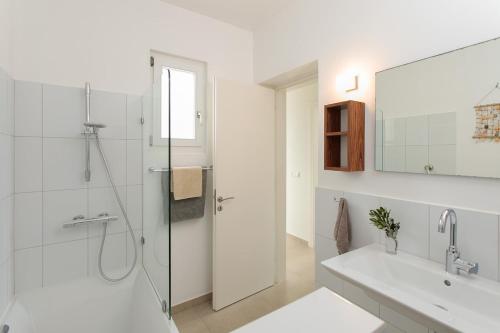 a white bathroom with a shower and a sink at Villa Almiriki, Stelida Naxos. in Naxos Chora