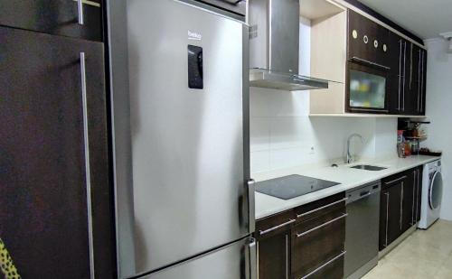 eine Küche mit einem Kühlschrank aus Edelstahl und einer Spüle in der Unterkunft APARTAMENTO 2 HABITACIÓNES con GARAJE EN SANTOÑA in Santoña