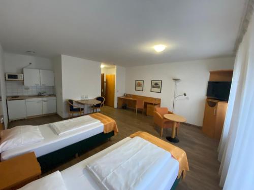 a room with two beds and a kitchen and a table at Ariva Boardinghouse Platanenhof in Mannheim