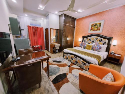 um quarto com uma cama, uma secretária e uma televisão em Hayyat Luxury Suites em Lahore