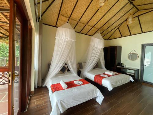 a bedroom with two beds with white drapes at Ta Xua Ecolodge in Bắc Yên