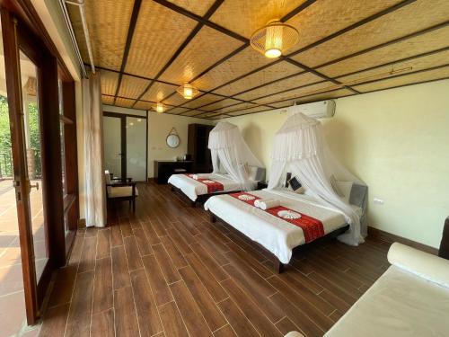 a bedroom with two beds with white comforters at Ta Xua Ecolodge in Bắc Yên