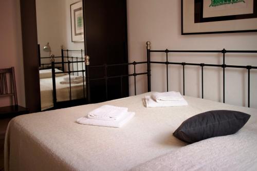 a bedroom with a bed with towels and a mirror at Sardinian Gallery Corso in Bosa