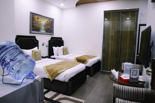 a hotel room with two beds and a television at Hayyat Luxury Hotel Suites in Lahore