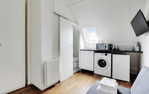 une salle de bains blanche avec un lave-linge et un lave-linge. dans l'établissement Amsterdam 12 - Charmant studio à Saint-Lazare, à Paris