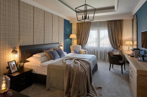 a bedroom with a bed and a desk with a chair at Andrássy Kúria & Spa in Tarcal