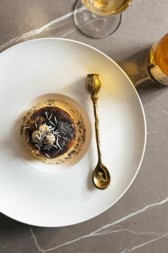 a white plate with a cup of coffee and a gold spoon at Andrássy Kúria & Spa in Tarcal