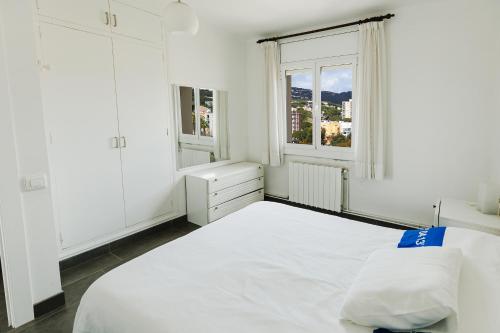 um quarto branco com uma cama grande e 2 janelas em Trevol 2 linea del mar em Platja d'Aro