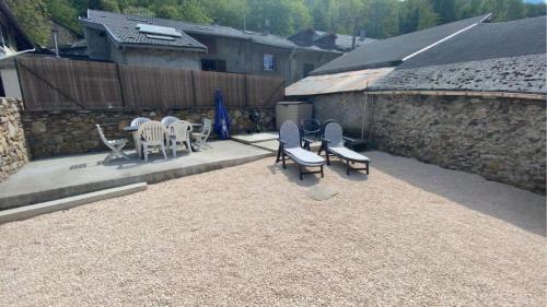 een patio met stoelen en tafels en een stenen muur bij Maison de famille rustique et rénovée Chez Mouichou in Gestiès