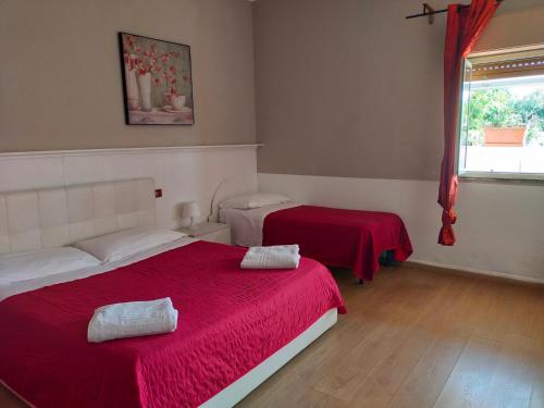 a bedroom with two beds with red sheets and a window at Hotel all'Antico Pozzo in Barcellona-Pozzo di Gotto