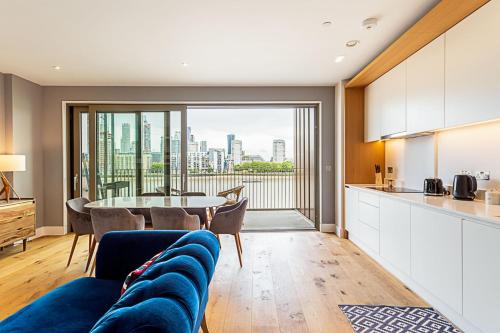 a kitchen and living room with a blue couch and a table at Stunning Surrey Quays Flat in London