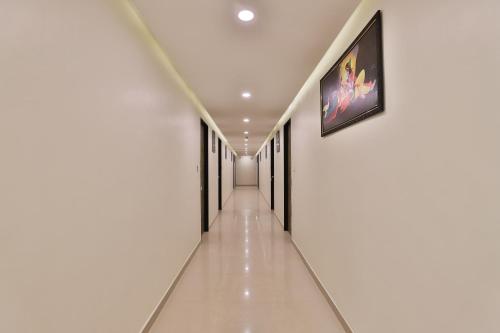 a hallway with white walls and a picture on the wall at Collection O 12462 Hotel Shiv Inn in Adalaj