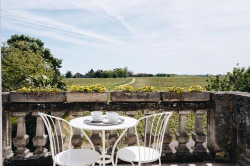 una mesa y sillas en un balcón con vistas a un campo en Le Château Réal, en Saint-Seurin-de-Cadourne
