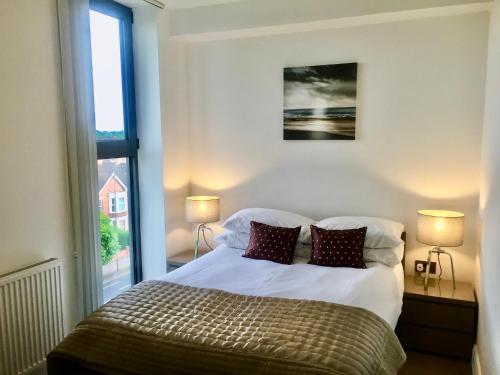 a bedroom with a bed with two lamps and a window at Castle Quarter - Free Parking - Fast Fibre in Bedford