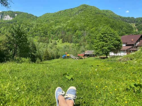 une personne avec ses pieds dans un champ d'herbe dans l'établissement Cabana Satic Piatra Craiului La Doi viermi, à Sătic