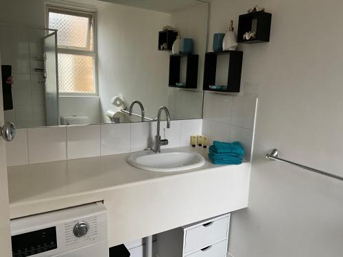 a white bathroom with a sink and a mirror at Lovely "Driftwood Taft" Apartment Beach & Everything few Minutes walk! Central Glenelg in Glenelg