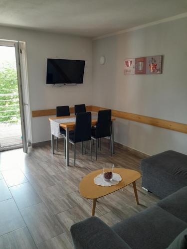 een woonkamer met een tafel en stoelen en een televisie bij Apartma Maks & Anita in Bovec