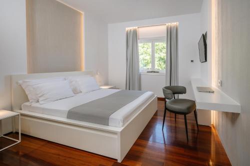 1 dormitorio blanco con 1 cama y 1 silla en BlueGreen Villa, en Karteros