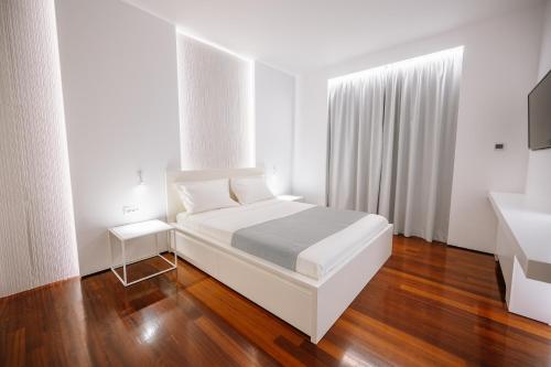 カルテロスにあるBlueGreen Villaの白いベッドとウッドフロアの白いベッドルームが備わります。