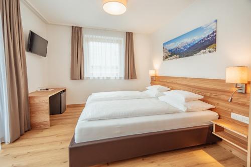 a hotel room with a bed and a television at Hotel Gesser in Sillian