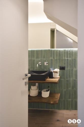 a bathroom with a green tiled wall with a bath tub at Vico37 Apartment in Acireale