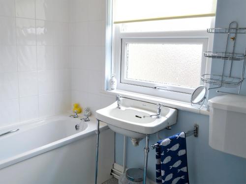 baño con lavabo, bañera y ventana en Beech Cottage, en Hepple