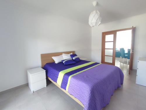 um quarto branco com uma cama roxa e uma janela em Bayside Holiday Home em São Martinho do Porto